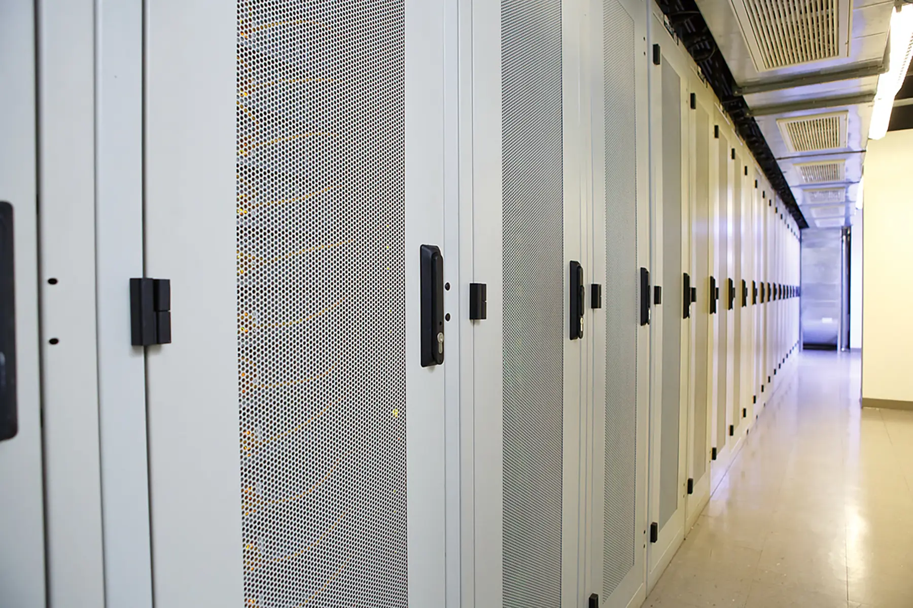 Secured ventilated equipment cabinets beneath data center cooling units